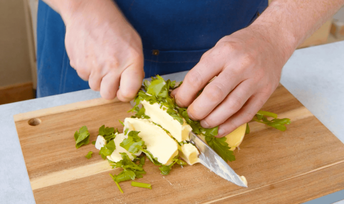 Butter wird mit Kräutern und Knoblauch kleingehackt